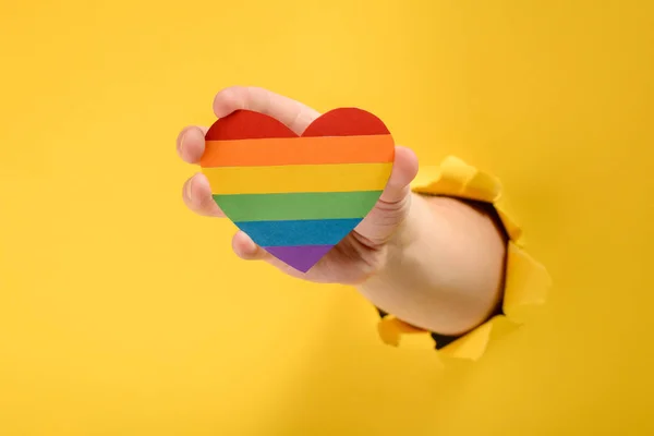 Hand holding a rainbow heart