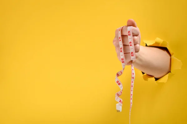 Mão segurando uma fita métrica — Fotografia de Stock