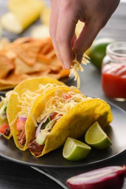 El taco üzerine peynir serpiştirir