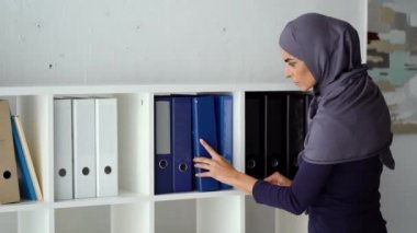 Sekreter belgeleri arıyor. Ofiste çalışan Müslüman kadın.