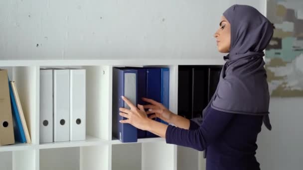 Muslim woman searching necessary information among folders — Stock Video
