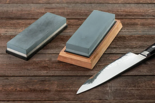 Japanese knife and two sharpenning stones on rustic wooden background — Stock Photo, Image