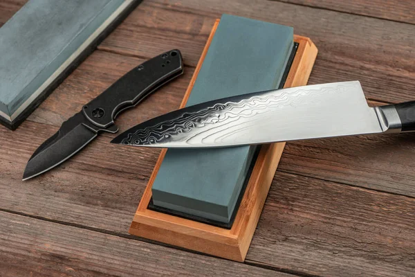 Kuchaři a kapesní nože a kamínky na rustikálním dřevěném stole — Stock fotografie