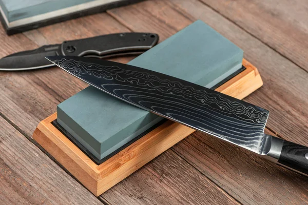 Afilar un cuchillo japonés Gyuto y un cuchillo con una piedra de afilar — Foto de Stock