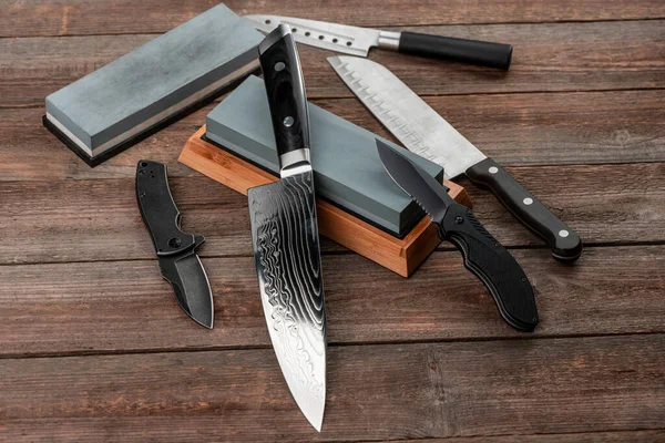 Assorted knives and sharpening stones on a rustic wooden table