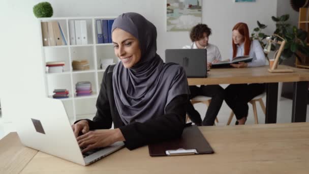 Μουσουλμάνα γυναίκα στέλνει μηνύματα σε ένα λάπτοπ κατά τη διάρκεια ενός διαλείμματος — Αρχείο Βίντεο