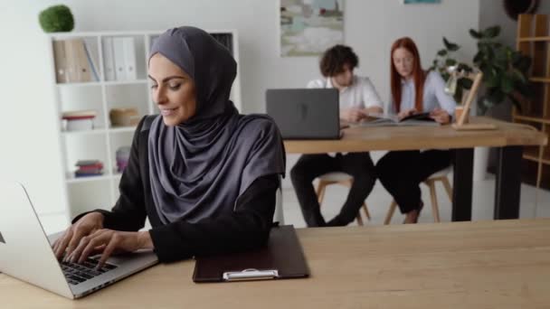 Donna musulmana che lavora su un computer portatile e scrive un testo — Video Stock