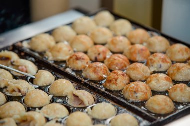 Özel bir tavada pişen Takoyaki toplarını yakından çek.