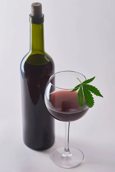 Склянка і пляшка червоного вина з інфузією конопель на білому тлі — стокове фото