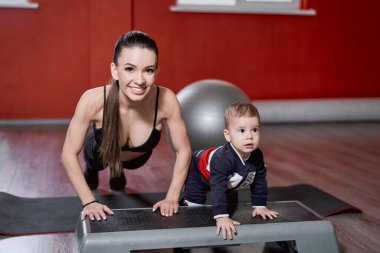 Anne yeni yürümeye başlayan çocuğuna nasıl şınav çekeceğini öğretiyor.