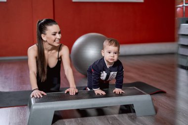 O ve küçük oğlu şınav çekerken genç anne gülümsüyor.