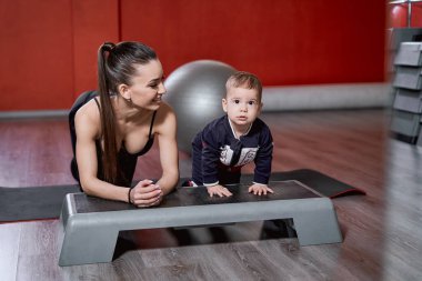 Kadın ve çocuğu spor salonunda egzersiz yapıyorlar.