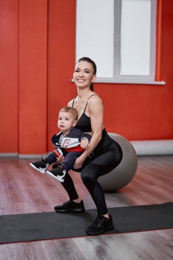 Çömelip çocuğunu kucağına alan bir kadın.