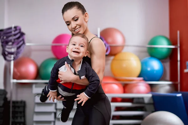 Spor salonunda annesinin ellerinde mutlu bir çocuk. — Stok fotoğraf