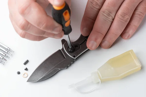 Close-up em mãos reparadoras montando as partes de uma faca de bolso — Fotografia de Stock