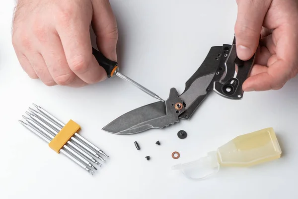 Repairman disassembling a folding knife with a screwdriver