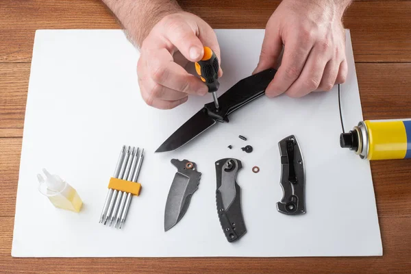 Man assembling a folding knife with a screwdriver
