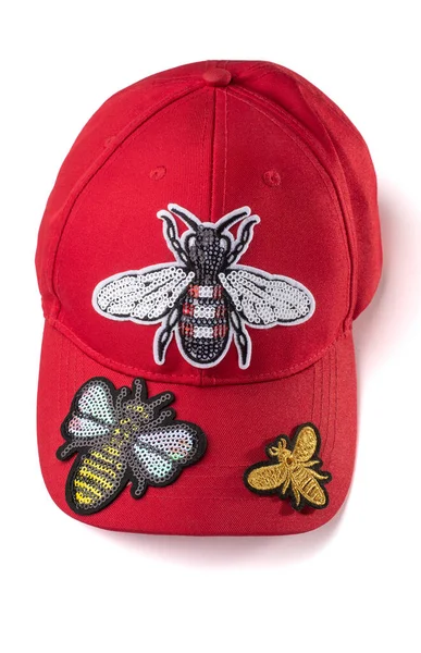 Red cap covered with insect sequin patches on white background — Stock Photo, Image