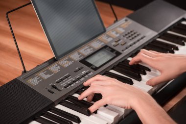 Piyano çalan ve tabletini notalarla kullanan bir adam.