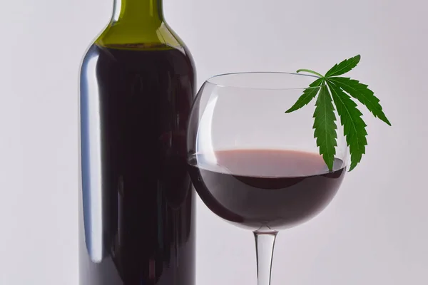 Bir bardak ve kenevir yaprağıyla süslenmiş kırmızı şarap.
