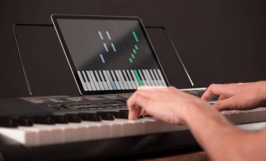 Genç öğrenci tabletinde bir uygulamayla piyano çalmayı öğreniyor.