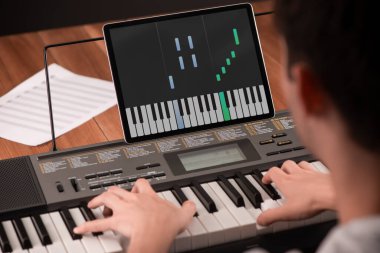 Adam tabletindeki bir uygulamanın yardımıyla piyano çalmayı öğreniyor.