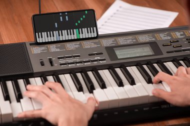 Adam piyano çalıyor ve telefonunun ekranına bakıyor.