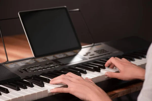 Молодий чоловік вчиться грати на піаніно, використовуючи клавіатуру і планшет з — стокове фото