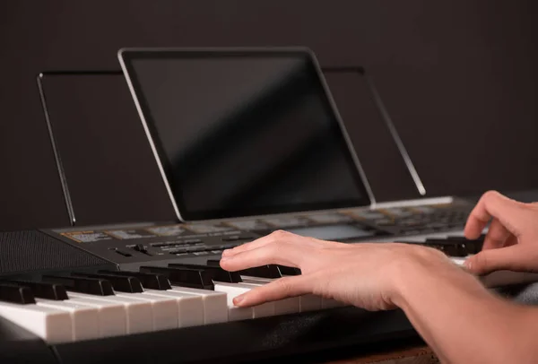 Человек играет на пианино и смотрит на ноты на планшете — стоковое фото