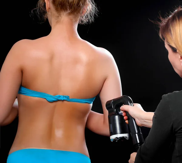 Woman body paint with airbrush in professional beauty salon