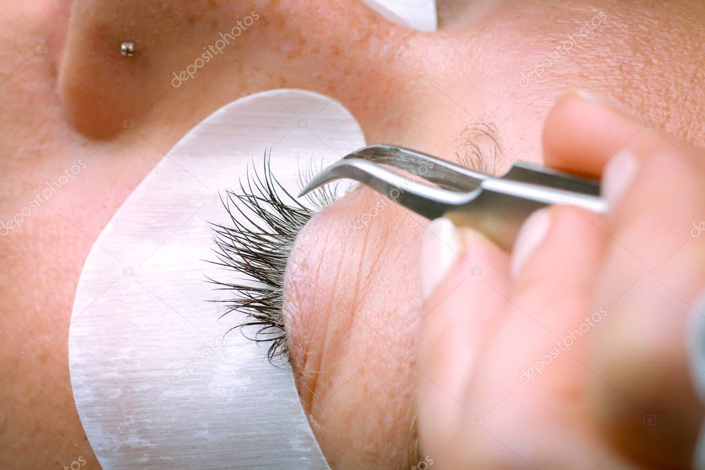 Eyelash extension procedure, woman eye with Long eyelashes