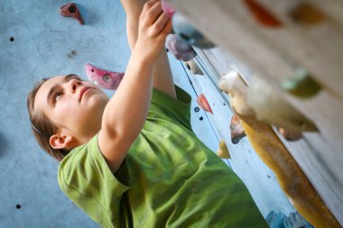 Genç çocuk üzerinde kapalı tırmanma duvarı tırmanma eğitimi