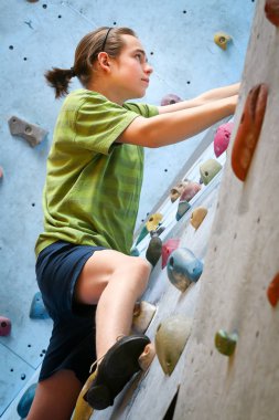 Genç çocuk üzerinde kapalı tırmanma duvarı tırmanma eğitimi
