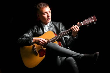 Siyah arka planda gitar çalan genç adamlar