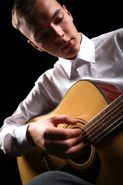 Young men playing the guitar with black background