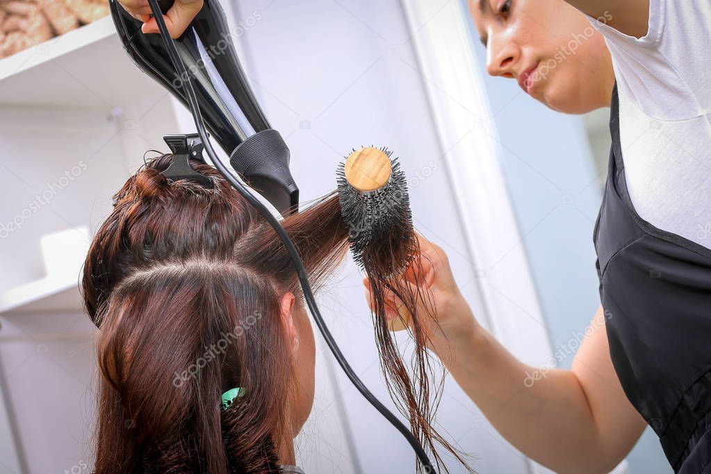Girl in beauty salon while an hair stylist dry her hair