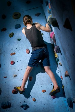 Genç çocuk üzerinde kapalı tırmanma duvarı tırmanma eğitimi