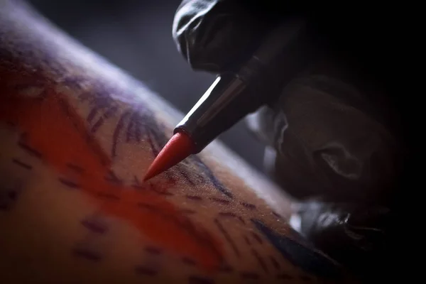 Female tattoo artist making tattoo on a men`s arm
