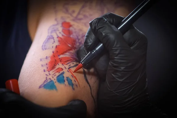 Tatuagem feminina fazendo tatuagem no braço de um homem — Fotografia de Stock