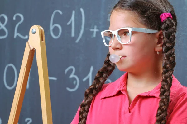 Happy school girl in front of the blackboard