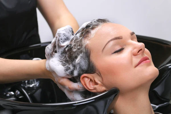 Cabeleireiro lavar o cabelo da mulher no salão de cabeleireiro — Fotografia de Stock