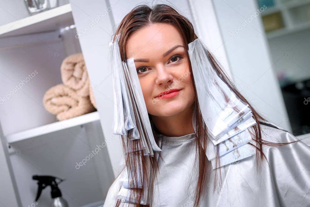 Girl in beauty salon while an hair stylist dyeing her hair