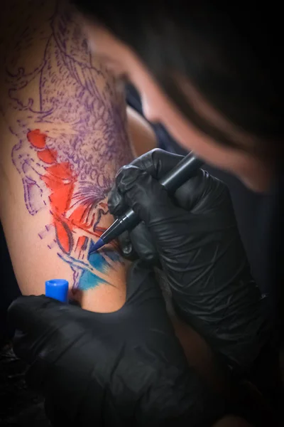 Kvinnlig tatuering konstnär gör tatuering på en herr arm — Stockfoto