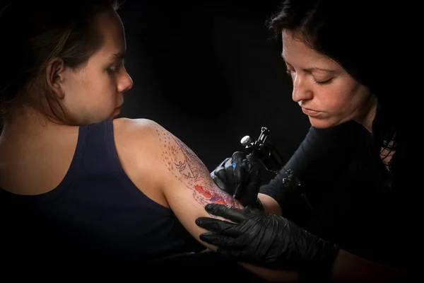 Kvinnliga tatuerare att göra tatuering på en mäns arm — Stockfoto
