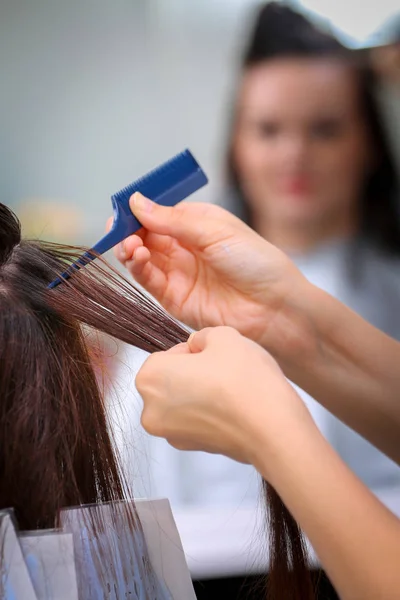 Meisje in de schoonheidssalon, terwijl een kapper die haar haren verven Stockfoto