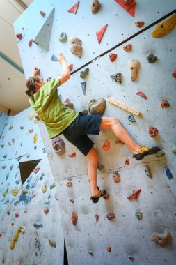 Genç çocuk üzerinde kapalı tırmanma duvarı tırmanma eğitimi