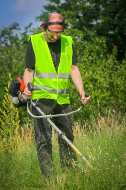 Çim biçme makinesiyle çim biçen işçiler