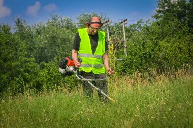 Çim biçme makinesiyle çim biçen işçiler