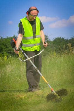 Çim biçme makinesiyle çim biçen işçiler