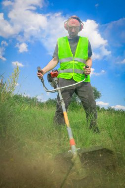 Çim biçme makinesiyle çim biçen işçiler